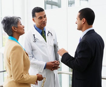 Médecin dialoguant avec une femme et un homme d&#39;affaire