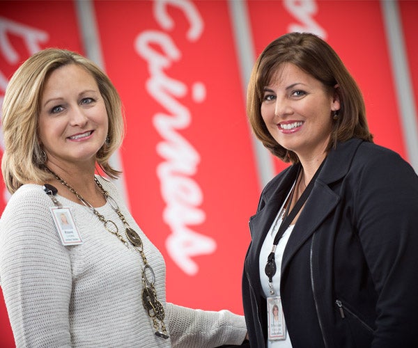 Two female Associates standing in a hallway