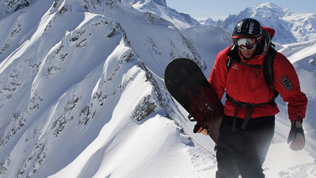 A snowboarder climbing a snowy mountain